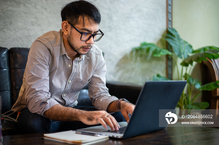 Asian businessman typing on laptop and working in home office