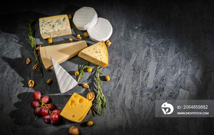 Different sorts of cheese. Cheese platter with different cheese, and spices on dark background. Top 