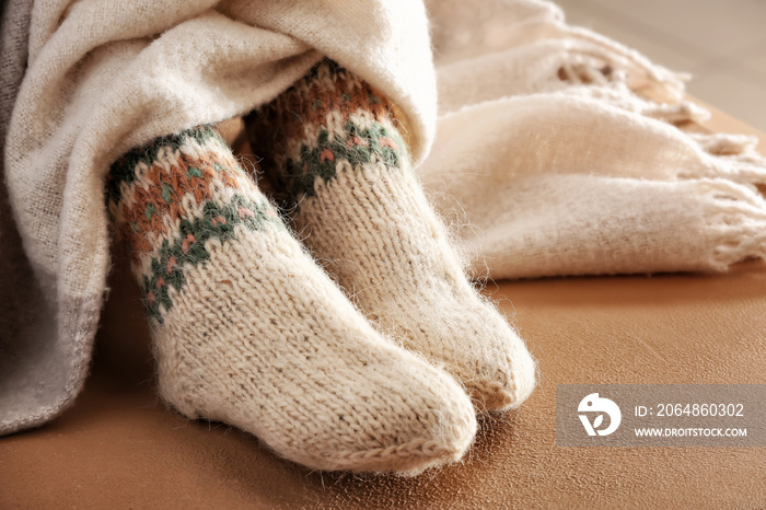 Legs of woman in knitted socks and plaid on color background