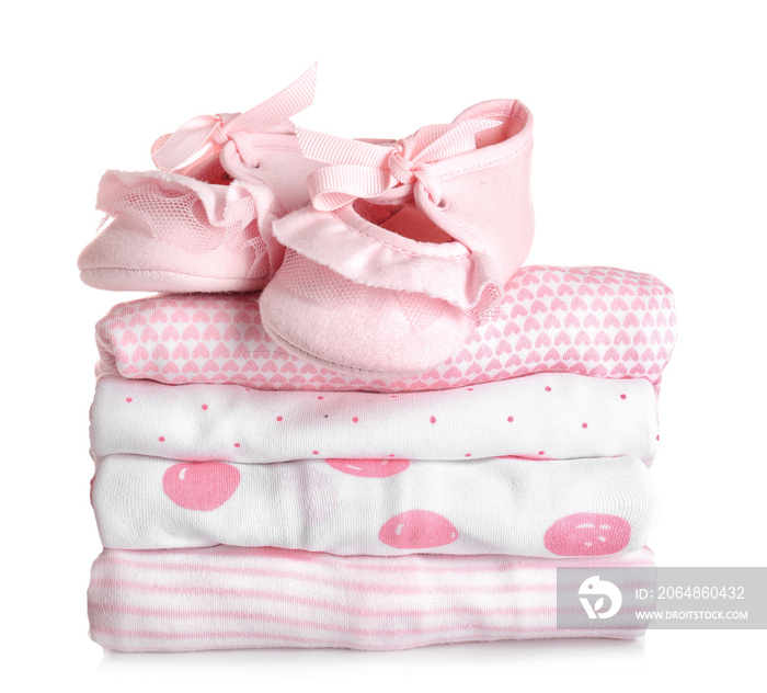 Stack of baby clothes and shoes on white background