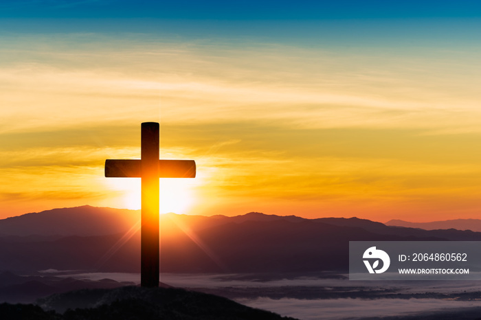 Silhouette of cross on mountain sunset background.