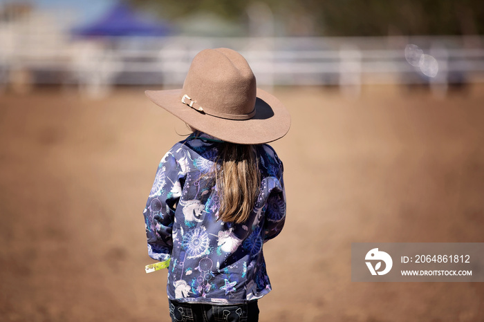 Little Cowgirl Standing In The Dust Watching A Rodeo