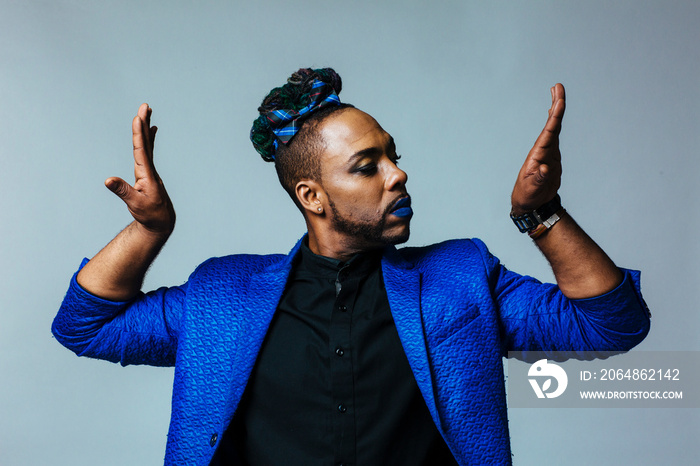 Studio portrait of a man with blue outfit and blue lips. Strong man