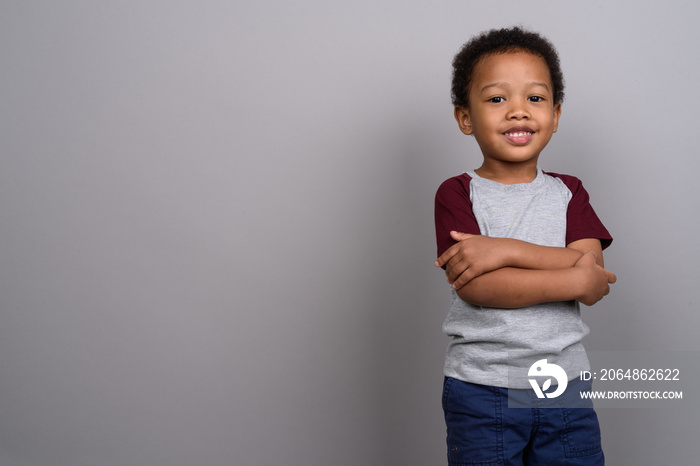 Young cute African boy against gray background