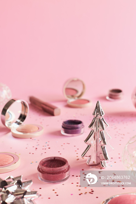 粉色背景的美容产品和圣诞装饰。圣诞和新年派对化妆概念。