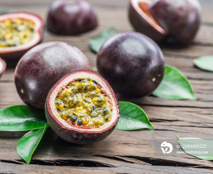 Passion fruits and its cross section with pulpy juice filled with seeds. Wooden background.