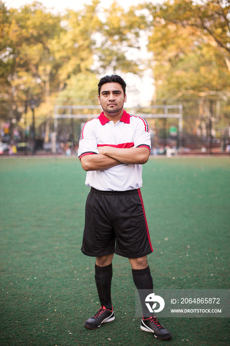 Soccer player standing with arms crossed in soccer field