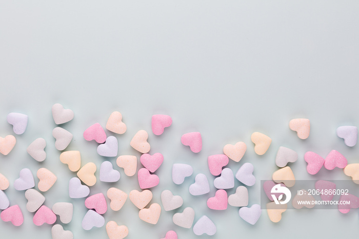 Composition with candy hearts on pastel blue background.