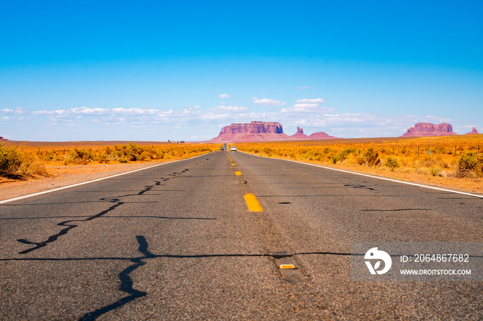 Endless infinite road that goes through the Monument Valley National park with amazing rock formatio