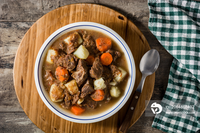 Irish beef stew with carrots and potatoes on black background. Top view.