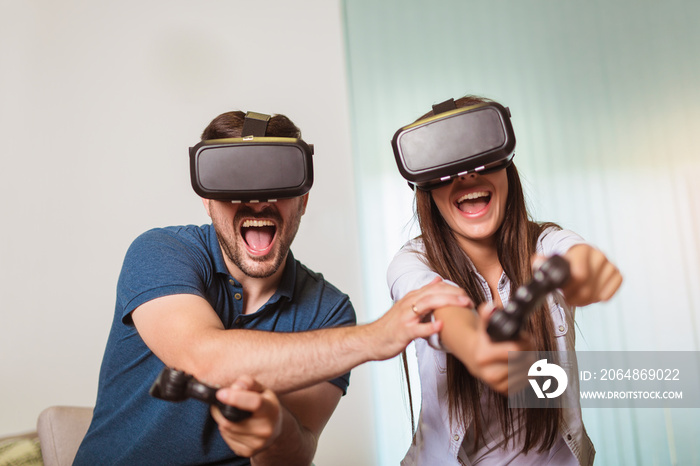 Young happy couple playing video games virtual reality glasses. Couple having fun with new trends te