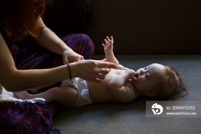 Mother changing baby girls (6-11 months) diaper