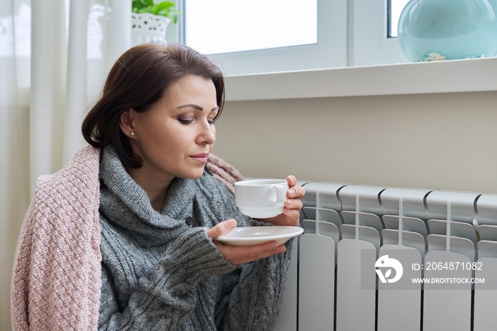 冬季，妇女在家庭供暖散热器附近取暖