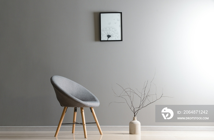 Stylish chair with vase near grey wall in room