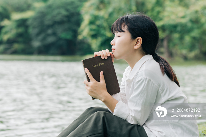 Woman holding a Bible, a natural background, is faithful to God and love God’s word