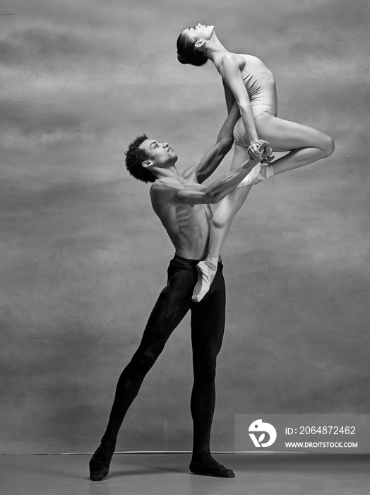 Couple of ballet dancers posing over gray background