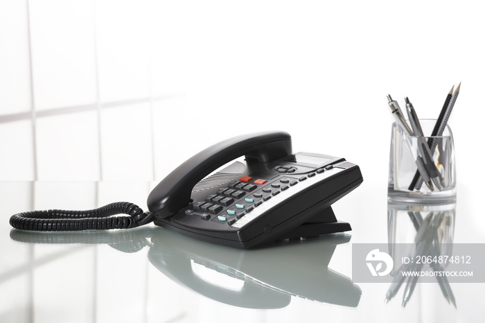 Landliine black phone on an office desk.