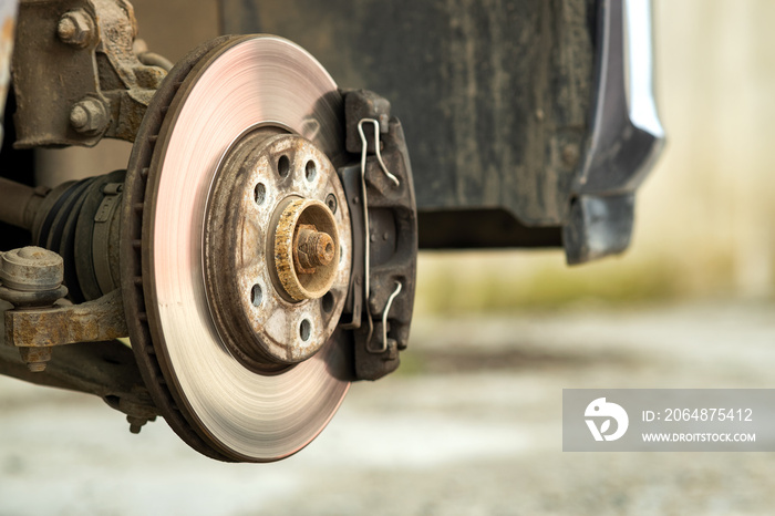 Closeup of braking disc of the vehicle with brake caliper for repair in process of new tire replacem