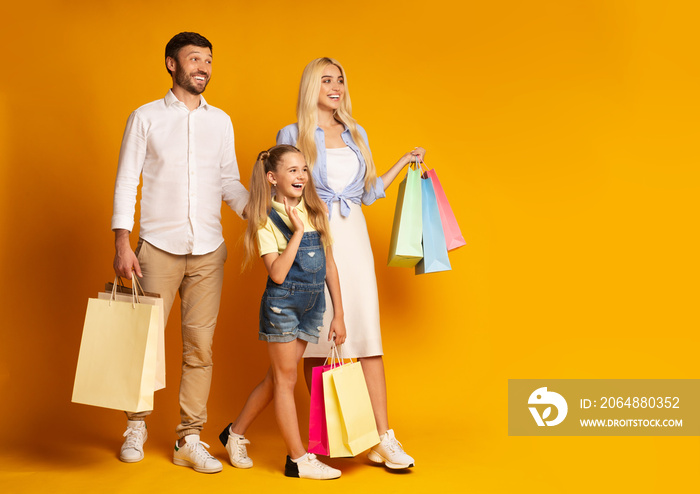 Parents And Daughter Walking Holding Shopping Bags, Yellow Background