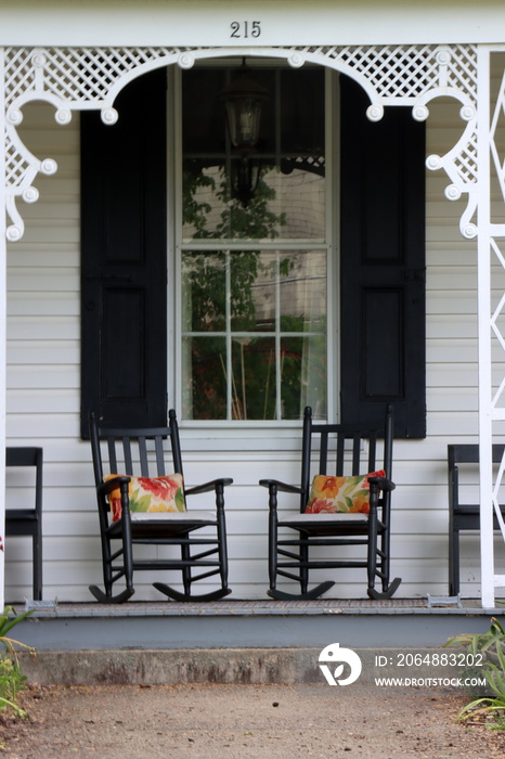2 wooden rocking chairs in the front of a house