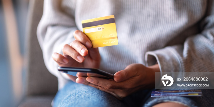 Closeup image of a woman using credit card for purchasing and shopping online on mobile phone