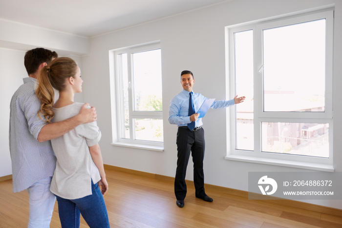 realtor with clipboard and couple at new home