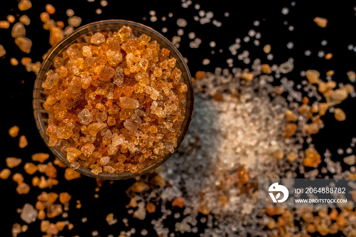 Close up shot of gond/goond/edible gum crystals in a transparent glass bowl on a black glossy surfac