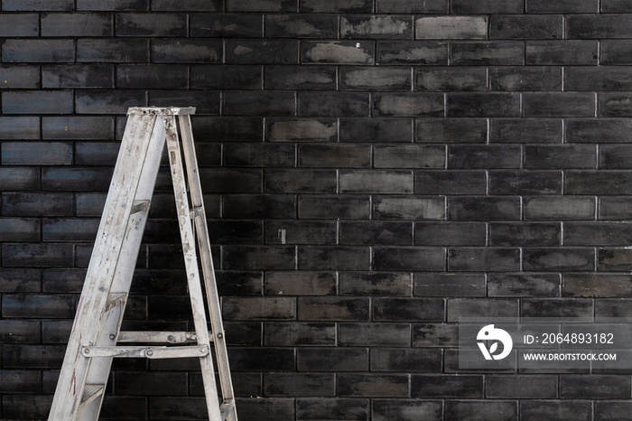 Aluminum staircase against black brick wall background.