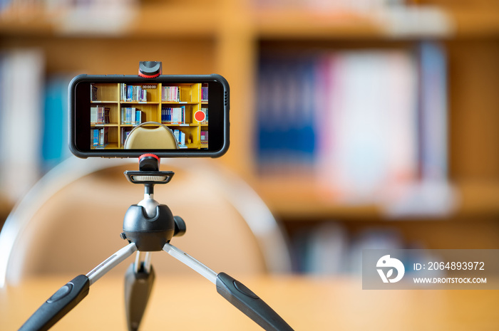 A mobile phone mounted on a tripod is used to teach students online at the library.