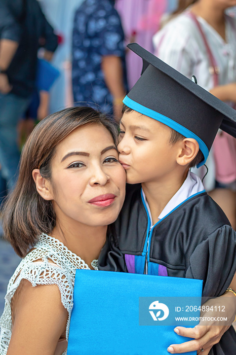 Portrait son graduated from kindergarten kissing mother