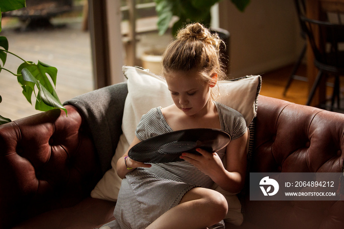 High angle view of cute girl holding turntable while relaxing on sofa at home