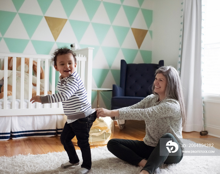 Side view of happy mother catching playful son running away at home