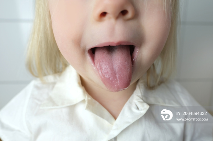 little child, baby, blonde girl showing tongue, mouth close-up, , concept of speech disorders, corre