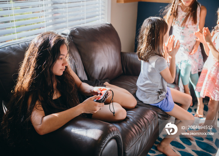 年轻女子在家沙发上放松时玩电子游戏