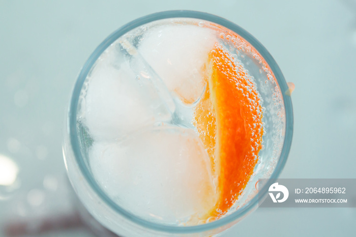 glass with oranges, ice, sparkling water close-up