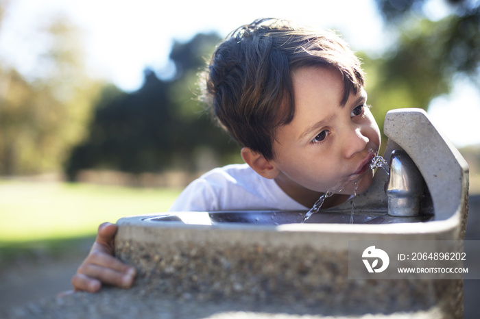 Boy drinking water from faucet