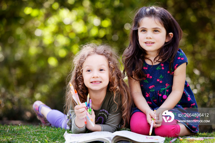 Cute girls looking away while relaxing on field