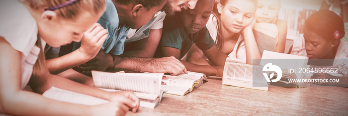 Teacher and kids lying on floor reading book in library