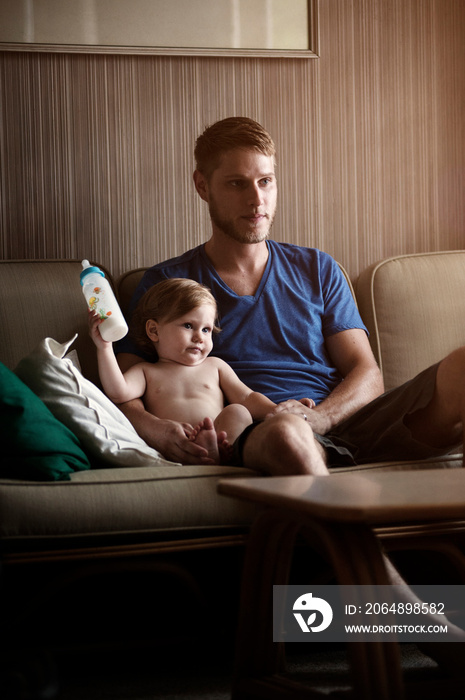 Father sitting with baby son (12-17 months) on sofa