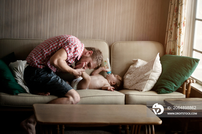 Father kissing his sons feet on sofa