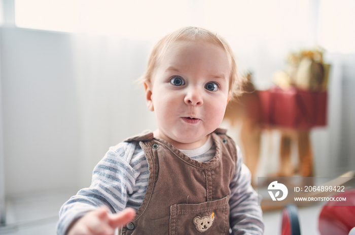 Portrait of a cute 1 year old baby boy sitting on the floor. christmas decorations on a background