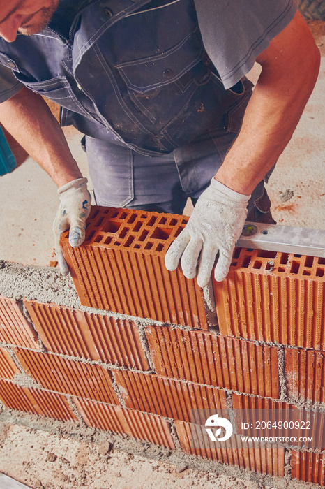 Real construction worker bricklaying the wall indoors.