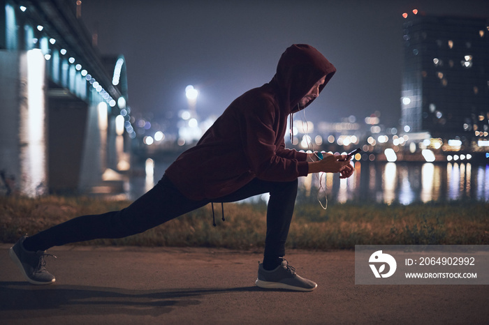 Athletic sporty man training in hoodie sweatshirt in urban / city environment.