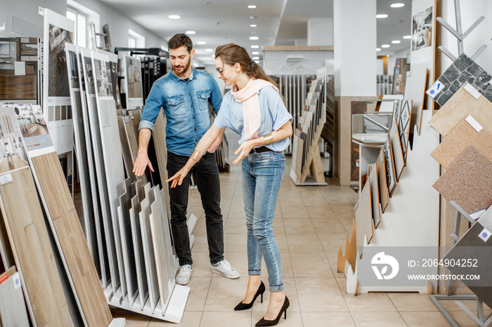 Beautiful young couple choosing ceramic tiles for their house repairment in the building shop