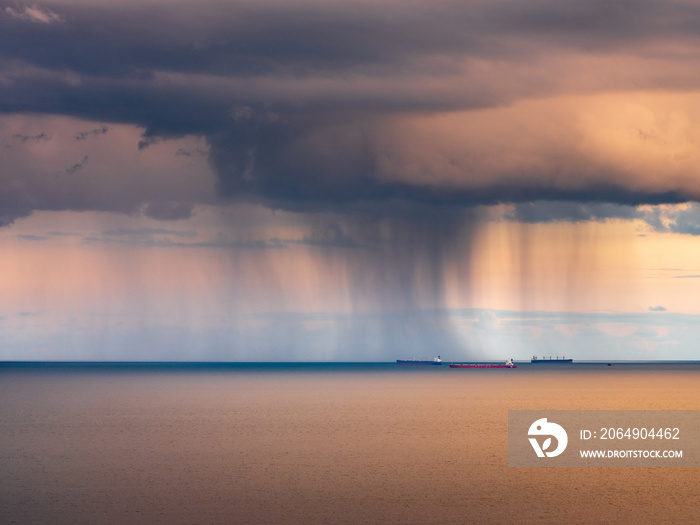 view to vessels at the sea under dark clouds and strong rain in sunset time with copy space