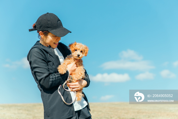 スポーツウェアで犬の散歩をする女性（抱く）