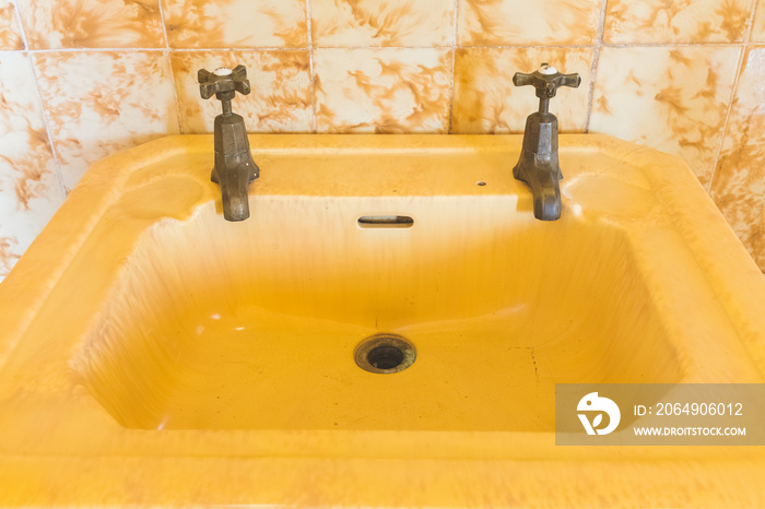 Closeup of vintage yellow bathroom sink and taps (selective focus)