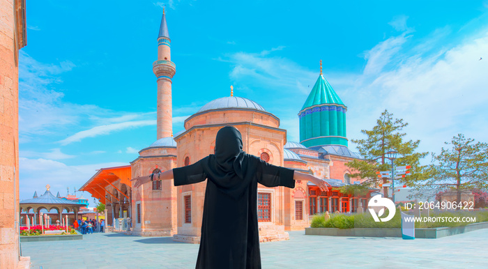 年轻女孩穿着长袍，双臂高举，开心不已——土耳其科尼亚的梅夫拉纳博物馆清真寺