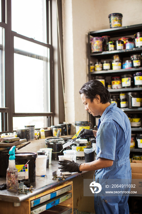 Worker with paint cans in workshop