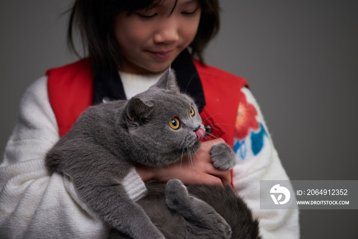 一个亚洲小女孩抱着一只可爱的英国短毛猫